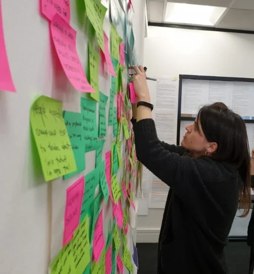 Sara Lopez writing on a wall of sticky notes during a workshop