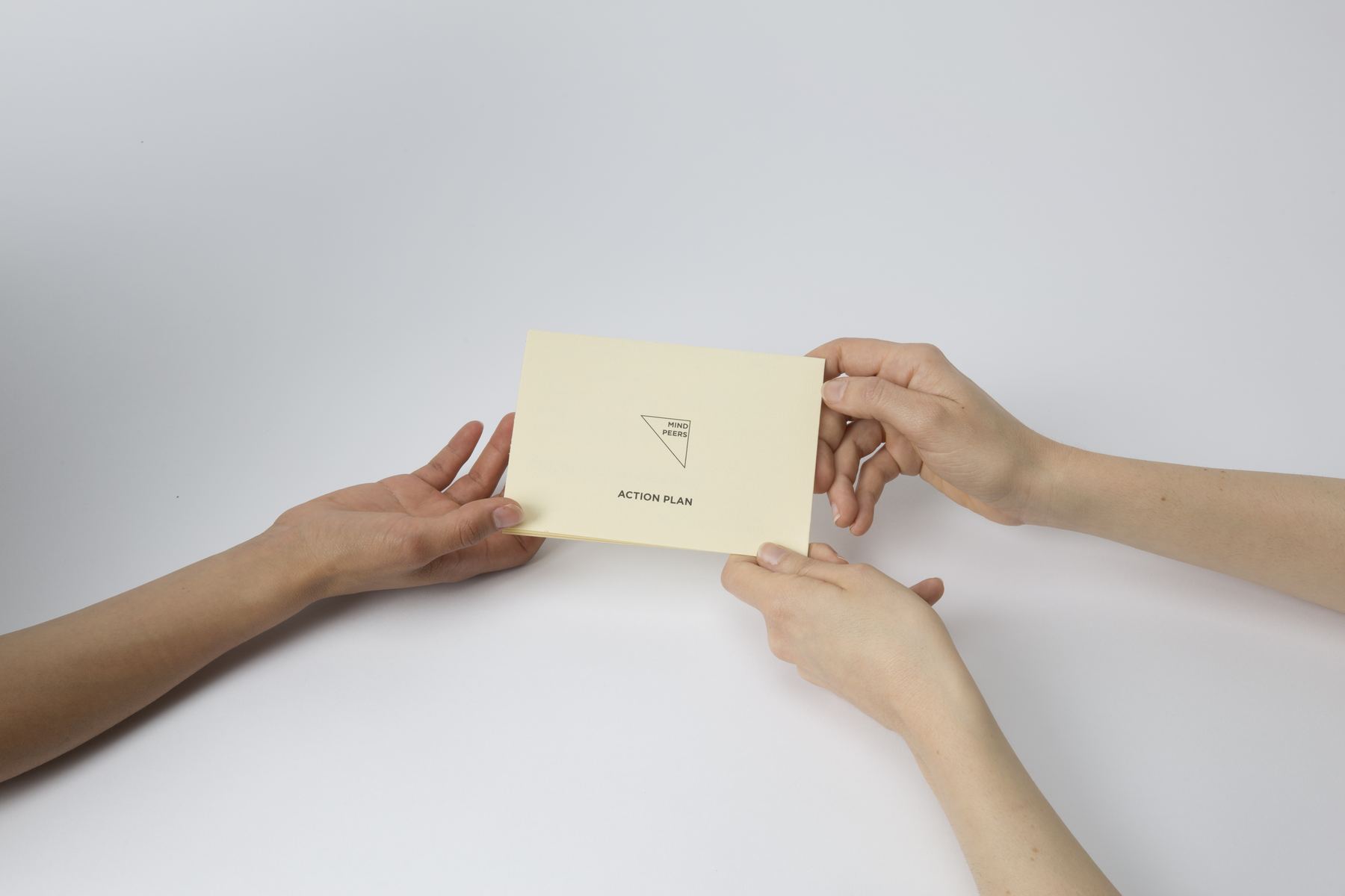 Two people passing a Mind Peers action plan card across a table