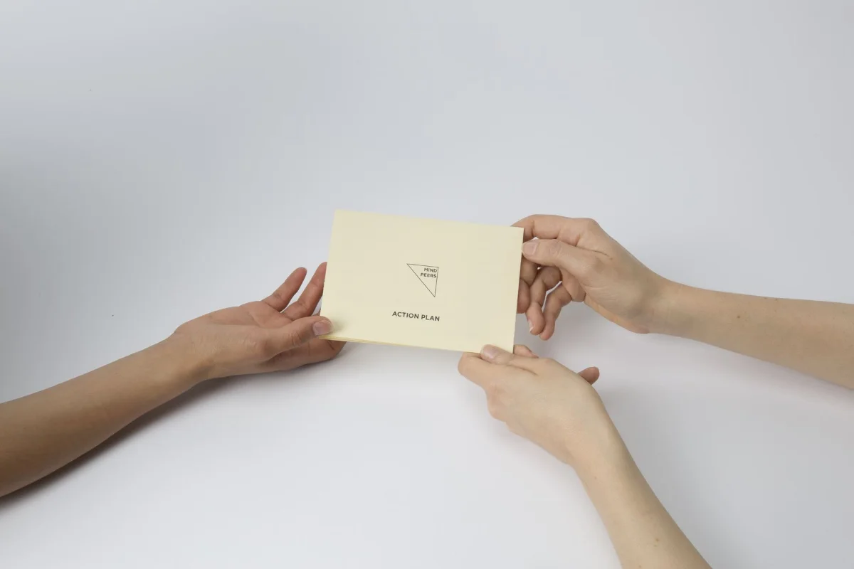 Two people exchanging a Mindnosis action plan card